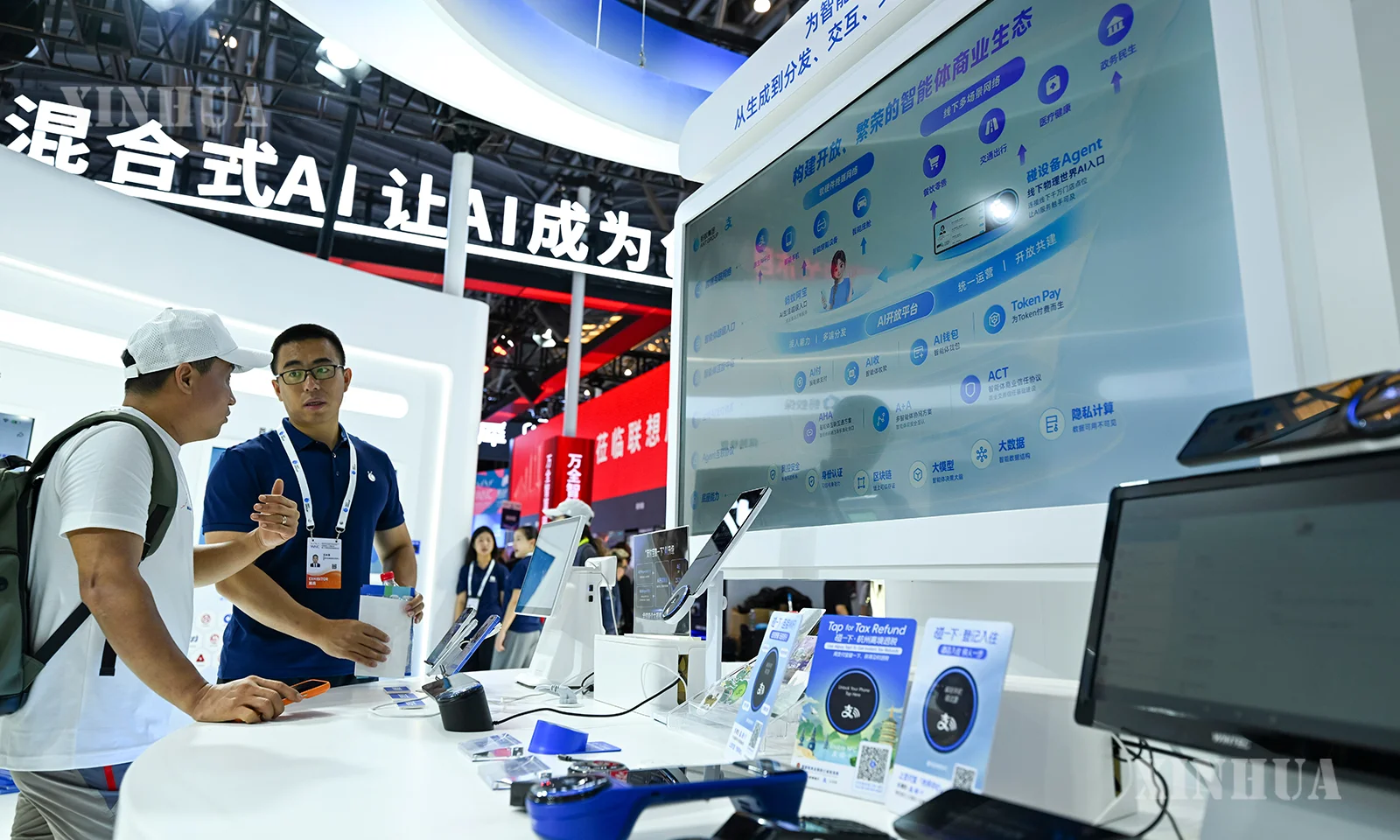 တရုတ်နိုင်ငံ ရှန်ဟိုင်းမြို့တွင် Ant Group ပြသခန်းမှ ဝန်ထမ်းတစ်ဦး (ယာ) က AI နည်းပညာသုံး စီးပွားရေးလုပ်ငန်းဂေဟစနစ်ကို လာရောက်ကြည့်ရှုသူတစ်ဦးအား မိတ်ဆက်ပြောကြားနေသည်ကို ၂၀၂၆ ခုနှစ် ဇူလိုင် ၁၉ ရက်က တွေ့ရစဉ် (ဆင်ဟွာ)